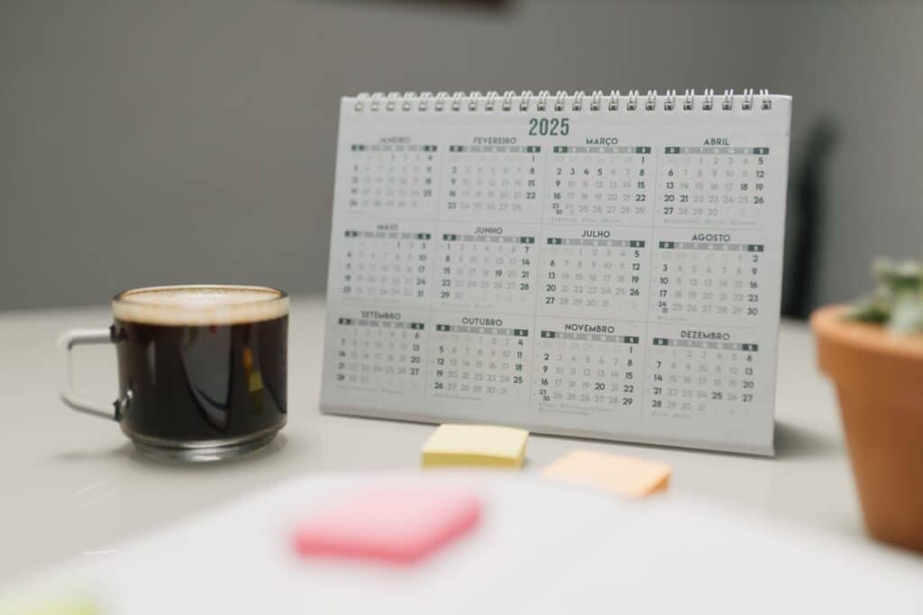 a 2025 desk calendar next to a cup of coffee and sticky notes.