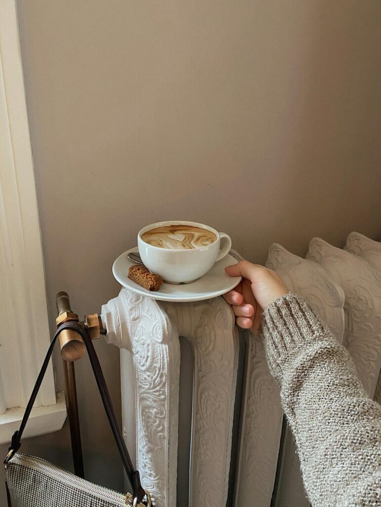 A coffee and dessert on a saucer that is being heated on the radiator.