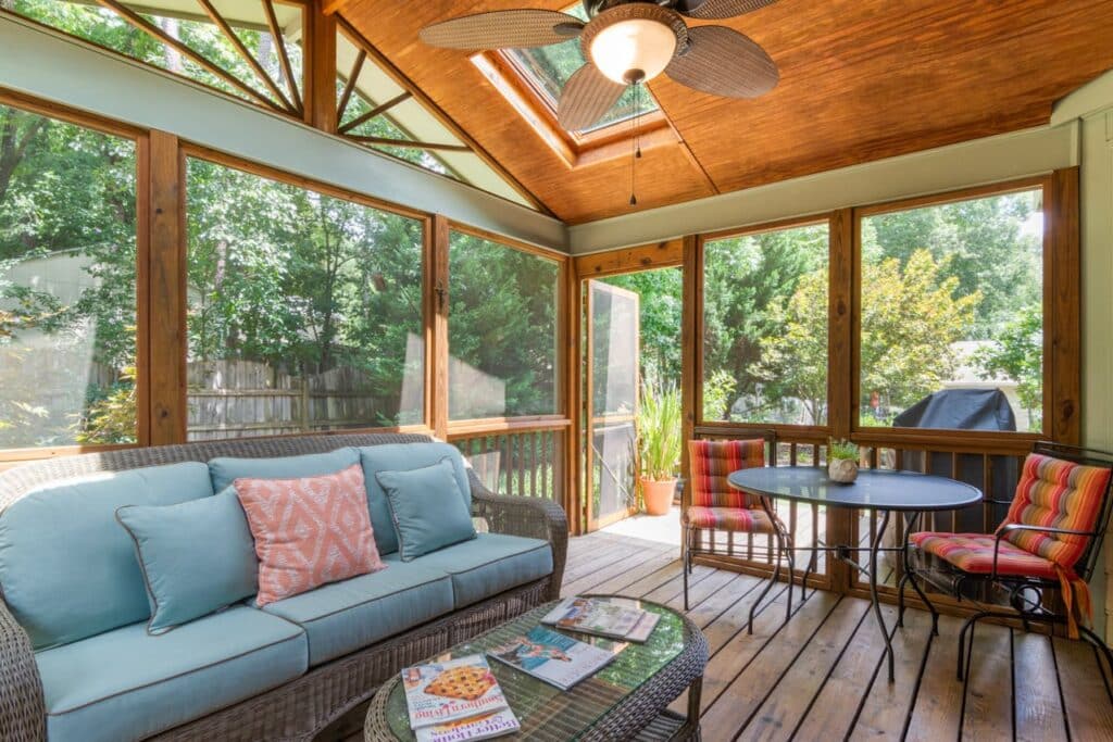 Screened in porch with ceiling fan and wicker furniture.