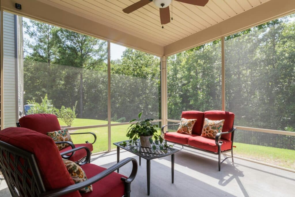 Screened in porch with ceiling fan and outdoor seating.