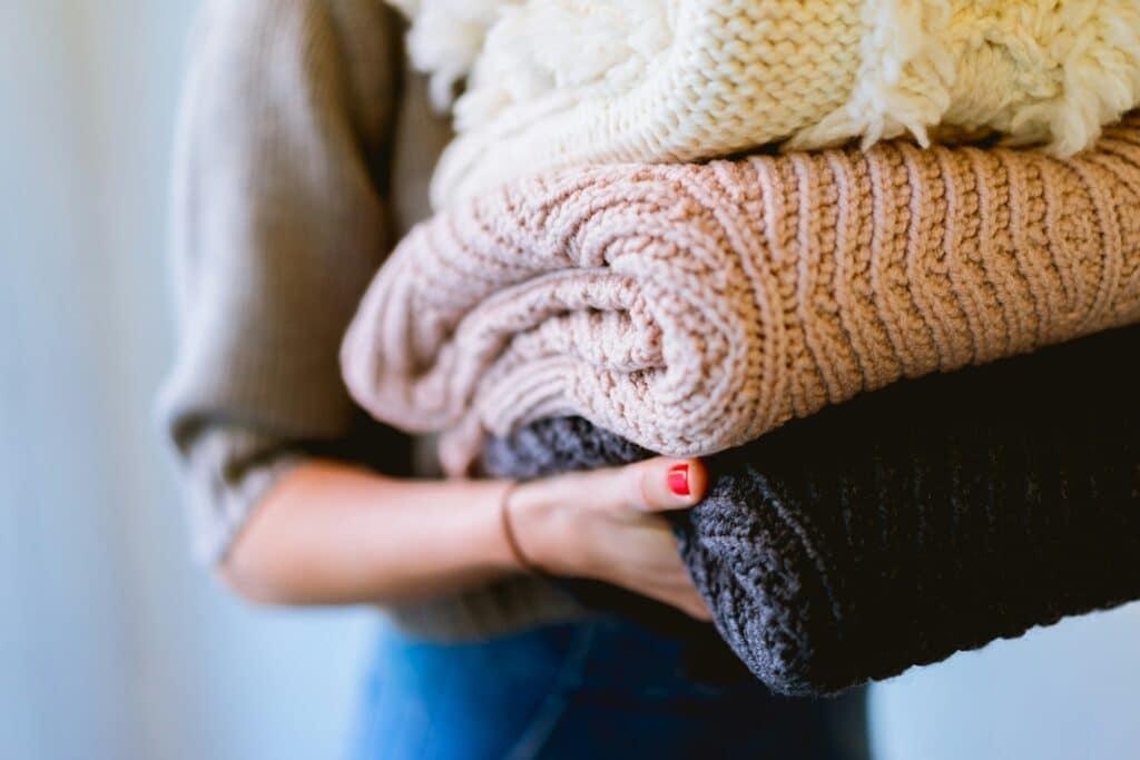 Woman holding a pile of folded blankets from the laundry.