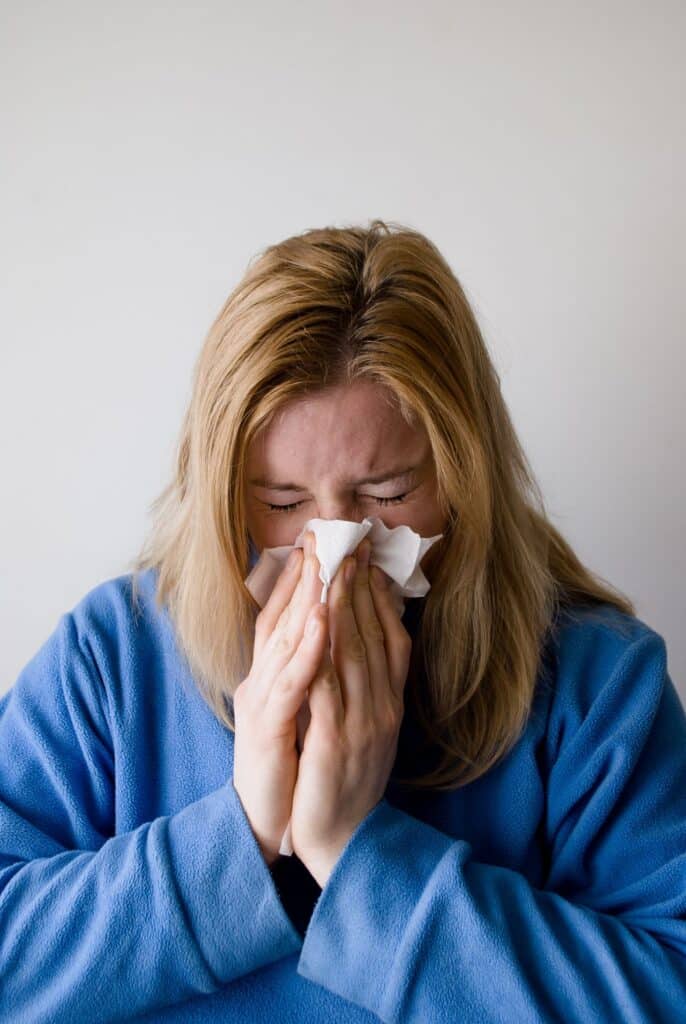 Woman blowing her nose due to indoor allergies.