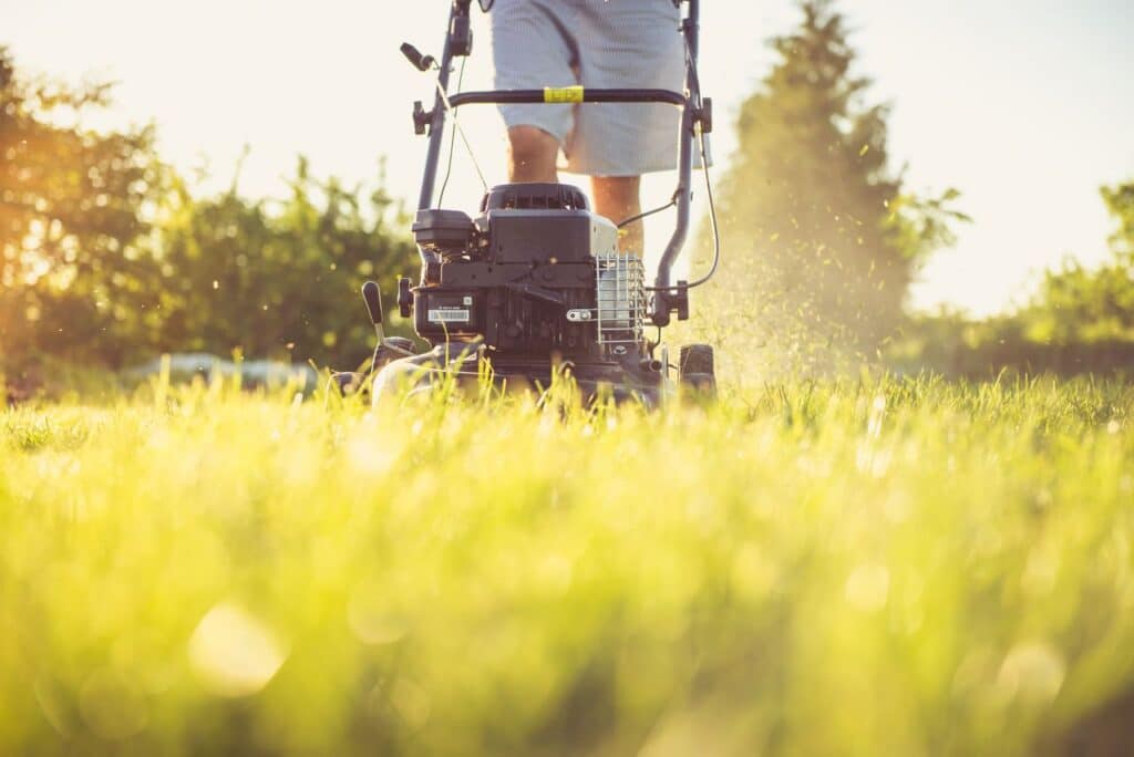 Man mowing grass around his air conditioner.
