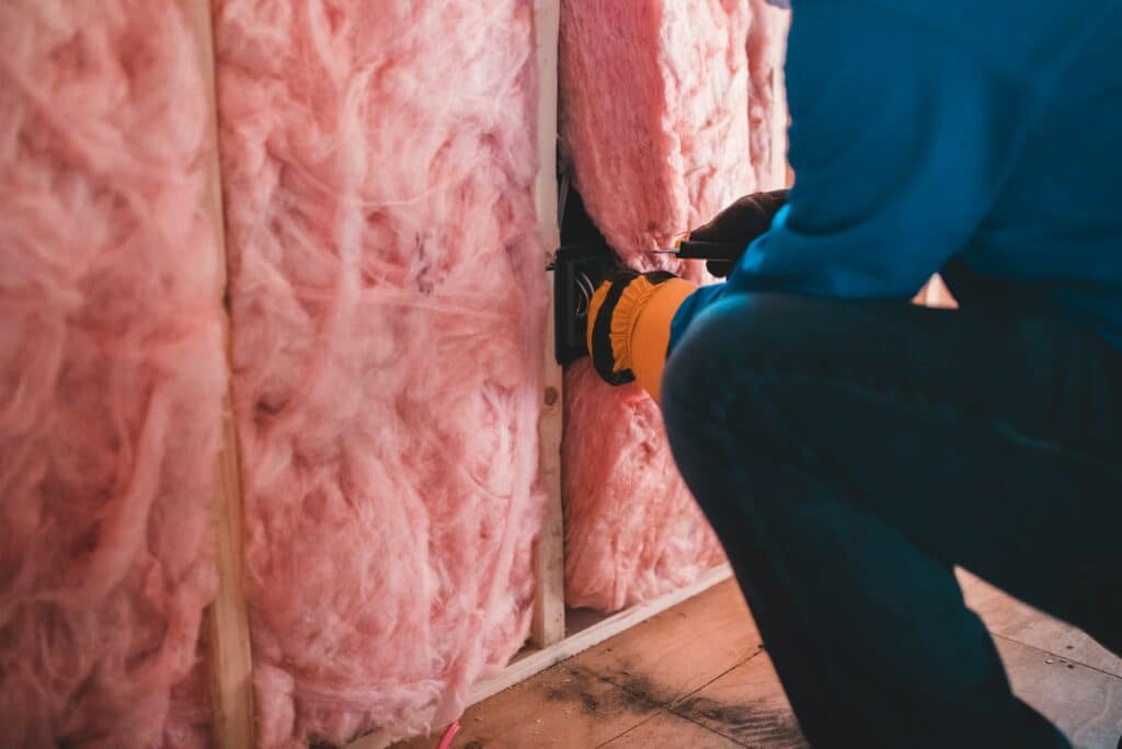 Image shows a contractor installing insulation in your attic to cool second floor.